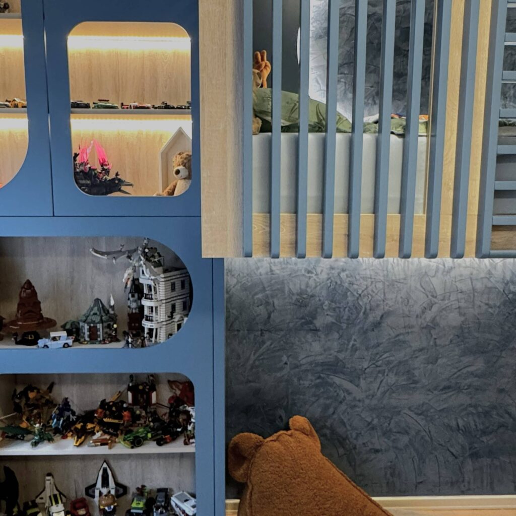 Plava soba s policama za LEGO modele i prostorom za kreativnu igru.