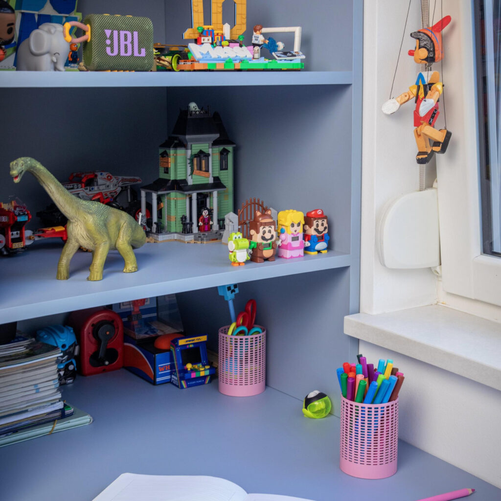 Radni stol u dječjoj sobi s otvorenim policama za LEGO modele, figurice i školski pribor